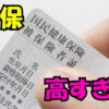 国民健康保険証を指で持っている写真に『国保 高すぎ！』の文字が大きく入っているイメージ