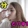 水分をとりすぎている女性がコップの水を飲んでいる様子