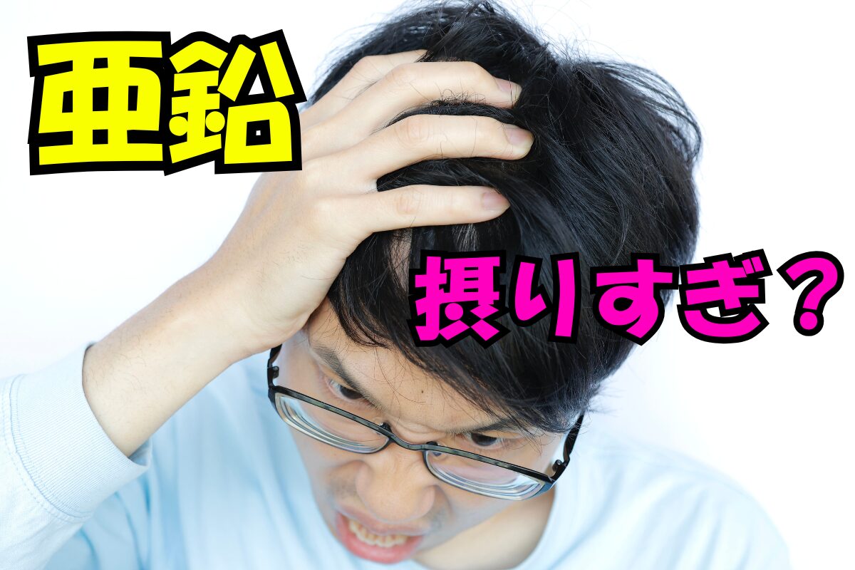 頭を抱えて苦しそうな男性。テキストに『亜鉛 摂りすぎ？』の文字