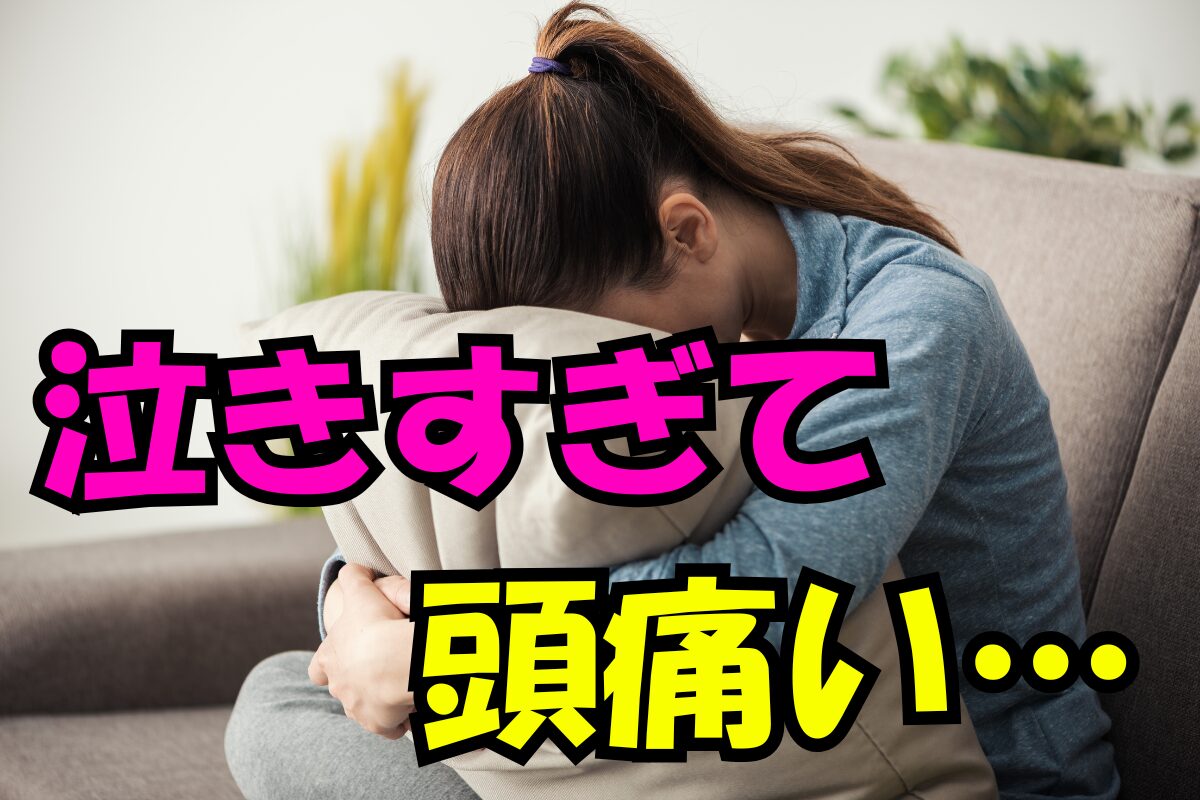 泣きすぎて頭痛いとソファでクッションに顔をうずめる女性